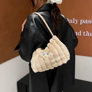 Sac à épaule chic en fausse fourrure beige avec nœud argenté et texture côtelée sur modèle