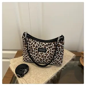 Detail view of leopard print crossbody bag with black leather trim and adjustable strap