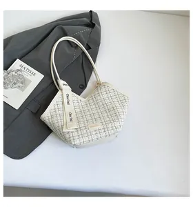 Detail of tweed bucket bag with V-shaped opening, decorative ribbon, and PU piping detail