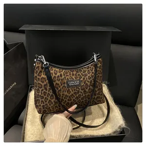 Detailed view of leopard print shoulder bag on gift box with silver hardware accents