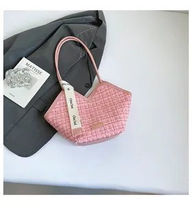 Detail of pink tweed bucket bag with woven texture and white decorative ribbon