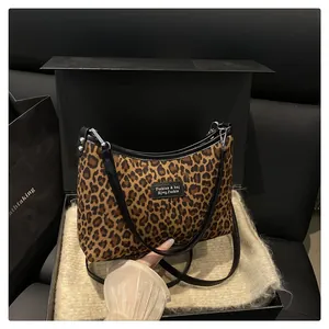 Detailed close-up of leopard print handbag with black leather trim and logo plate