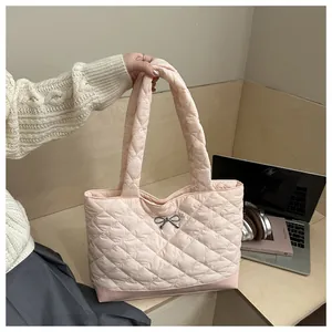 Close-up of pale pink quilted tote bag with a metal bow detail and soft puffy handles