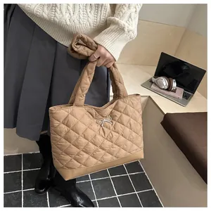 Close-up of khaki quilted tote bag featuring a decorative silver bow and padded texture