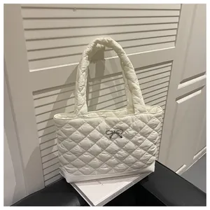 Detailed view of white quilted tote bag featuring a metallic bow and lattice pattern