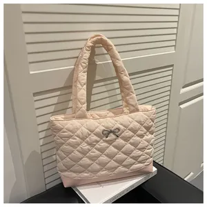 Detail of light pink quilted tote bag showing diamond texture and silver bow charm