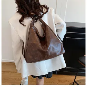 Detailed view of a dark brown vintage hobo bag worn with a chic white blazer outfit