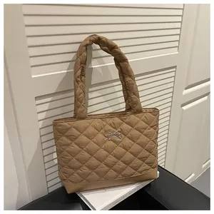 Macro detail of khaki quilted tote bag featuring a silver metal bow buckle and padded strap