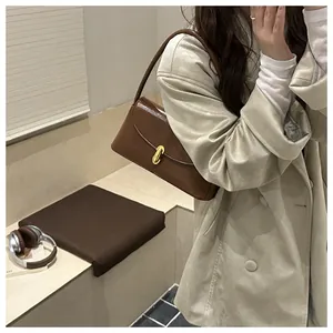 Brown leather underarm bag with gold metal buckle shown on a model in trench coat