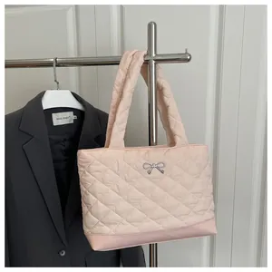 Close-up of pink quilted tote bag with silver bow detail and padded shoulder strap