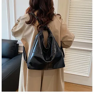 Model view of black high-gloss leather hobo bag with sleek shoulder straps and large capacity