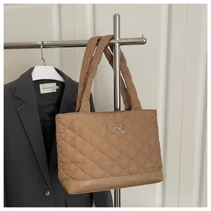 Close-up of caramel quilted nylon tote bag with silver bow and padded handles
