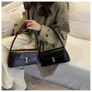 Detailed view of luxury leather shoulder bags with gold hardware on a cream sofa