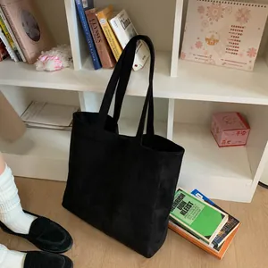 Detail of minimalist black large tote bag in matte suede with long shoulder handles