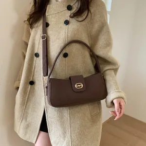 Close-up of a dark brown crossbody bag with a gold lock on a beige tweed coat
