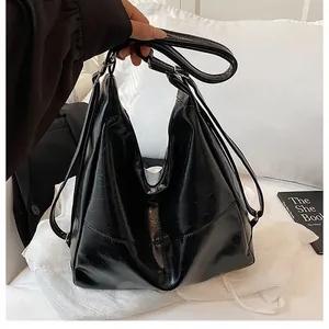 Detail showing the black glossy leather texture and metal buckle of the versatile tote bag