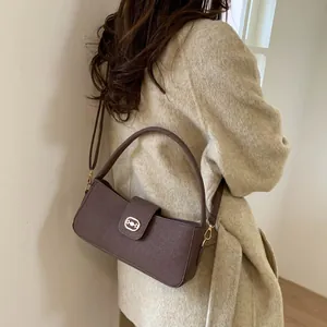 Brown lychee leather handbag worn by model on a beige wool coat for chic style