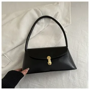 Detail of minimalist black leather handbag with a gold U-shaped metal buckle and round handle