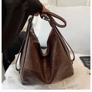 Close-up of vintage dark brown hobo bag in faux leather on a minimalist bed setting