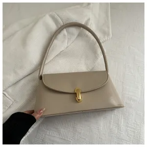 Detail view of a beige rectangular underarm bag featuring a gold oval metallic lock buckle