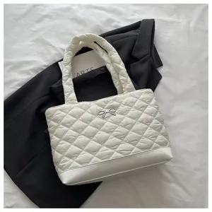 Detail of cream quilted tote bag showing lattice pattern and silver bow metal buckle