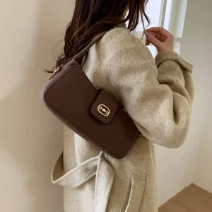 Detail view of dark brown wool fabric texture and gold buckle on stylish shoulder bag