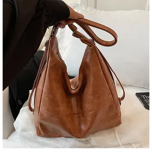 Close-up of vintage brown pebble leather tote bag with metallic zipper and adjustable strap
