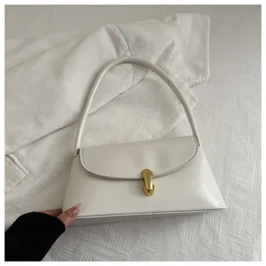 Detail of a creamy white handbag with a golden metal twist lock on a white fabric background