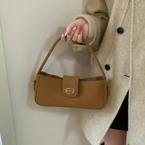 Detailed shot of tan faux suede baguette bag with golden buckle and sleek shoulder strap