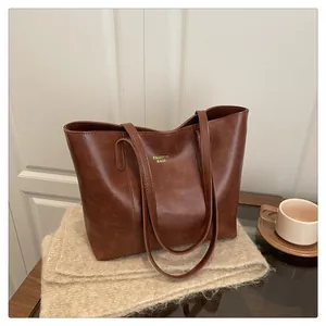 Detail van bruine vintage tote tas met gouden tekst op een wit gebreid kleedje