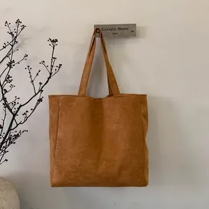 Detail view of brown corduroy tote bag texture and reinforced shoulder strap handle