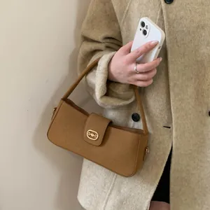 Close-up of brown suede shoulder bag with oval metal buckle on beige wool coat
