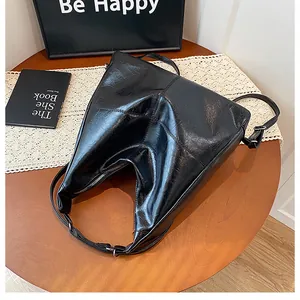 Top view of a black pleated faux leather shoulder bag on a wooden table with vintage decor
