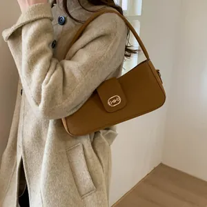 Detail of tan woolen baguette bag with golden buckle on a beige coat model