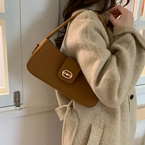 Detailed view of a brown vintage baguette bag with gold buckle on a beige wool coat