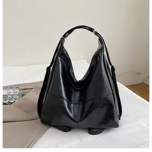 Detail of black glossy oil wax leather bag with pleated texture and silver ring hardware