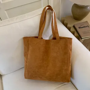 Detailed close-up of dark brown corduroy tote bag texture on a white sofa setting