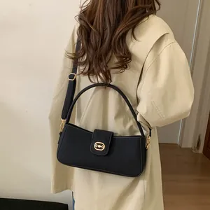 Detail of a black square handbag with gold circular metal buckle on a beige trench coat