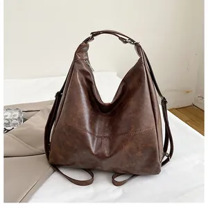Close-up of brown textured leather tote showing cross-stitch details and versatile handle