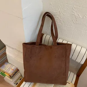 Detailed close-up showing the ribbed texture and wide straps of the dark brown tote bag