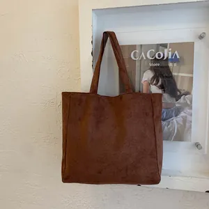 Detail of large dark brown tote bag in matte synthetic leather with long shoulder handles
