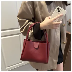 Detail view of burgundy leather bucket bag featuring a magnetic closure and sturdy dual handles