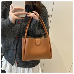Detail of caramel brown matte leather bucket bag with magnetic closure and dual handles