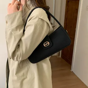 Detailed view of black textured leather handbag worn with a classic khaki trench coat