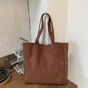 Close-up of brown suede tote bag showing soft matte texture and durable shoulder straps