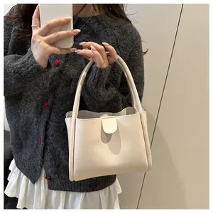 Mirror selfie showing a cream PU leather bucket bag with top handles and magnetic closure