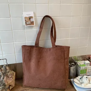 Detail of large dark brown tote bag made of corduroy fabric on a wooden table