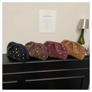 Detail of pleated clutch bags with leopard print, rivet studs, and matte texture finish