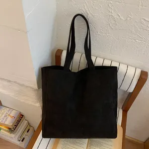 Minimalist large black tote bag with matte texture placed on a white chair in a home setting