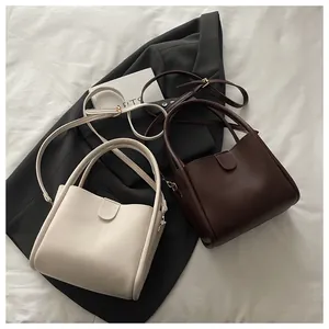 Flat lay of minimalist leather bucket bags in beige and brown with adjustable straps